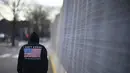 Seorang pejalan kaki berjalan melewati pagar keamanan yang mengelilingi Capitol menjelang pelantikan Presiden terpilih Joe Biden di Washington, Selasa (19/1/2021). Pelantikan Joe Biden berlangsung di tengah ancaman kekerasan dari pendukung Donald Trump dan pandemi Covid-19. (AP Photo/David Goldman)