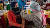 Seorang warga menerima vaksin virus corona COVID-19 Sinovac di pusat vaksinasi massal darurat di lapangan sepak bola di Surabaya, Jawa Timur, Kamis (30/9/2021). Vaksinasi ini dalam rangka percepatan penanganan COVID-19 dan pemulihan ekonomi nasional. (Juni Kriswanto/AFP)