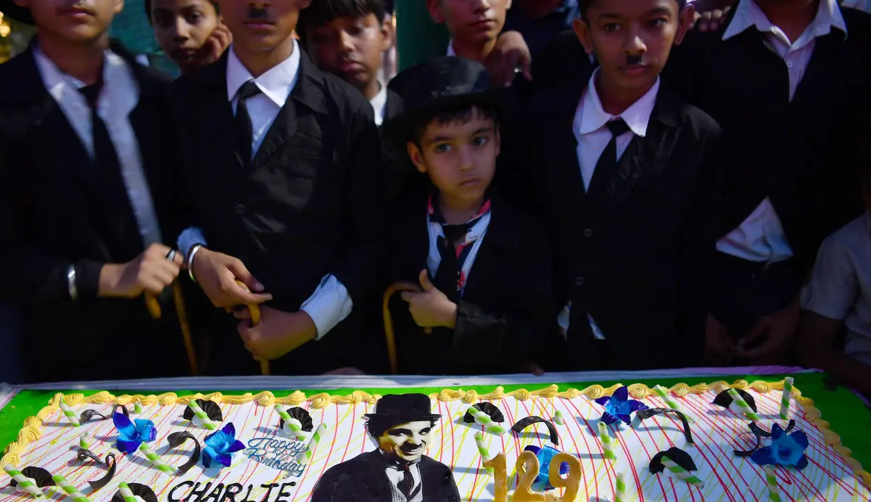 Sejumlah anak merayakan ulang tahun Charlie Chaplin di Adipur, India (16/4). Ratusan pengemar Charlie Chaplin mengenakan topi bowler dan kumis palsu membawa tongkat berjalan merayakan aktor komik tersebut. (AFP Photo/Indranil Mukherjee)