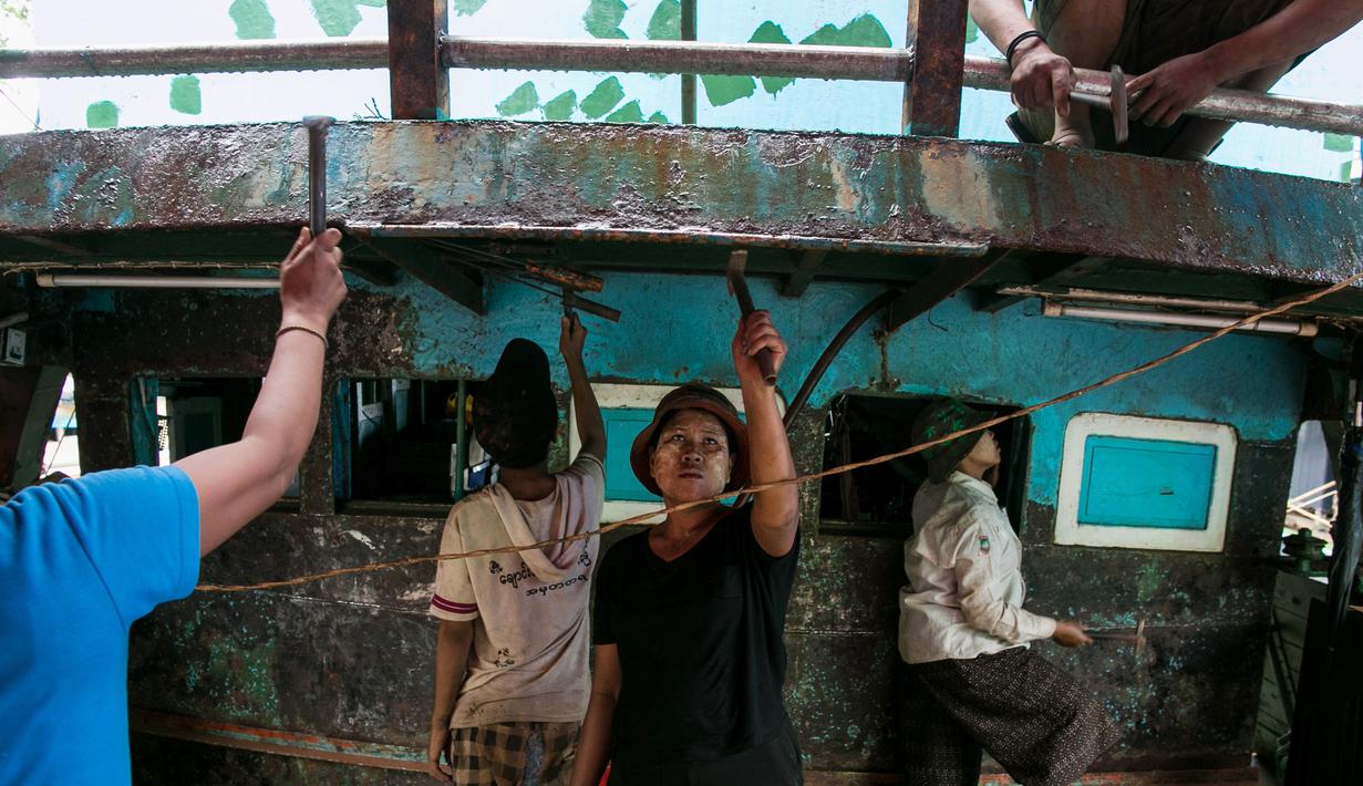 Para pekerja saat memperbaiki sebuah kapal di galangan kapal di tepi Sungai Yangon, yang terletak di pinggiran Yangon, Myanmar (30/7/2019). (AFP Phot/Sai Aung Main)