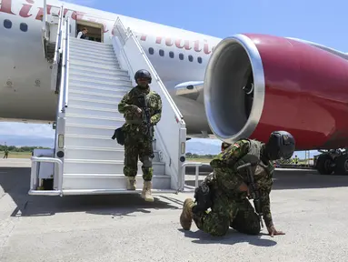 Petugas polisi Kenya yang merupakan bagian dari pasukan multinasional yang didukung PBB berlutut di landasan sebagai ucapan terima kasih setelah mendarat di Bandara Internasional Toussaint Louverture di Port-au-Prince, Haiti, Selasa (16/7/2024). (AP Photo/Odelyn Joseph)