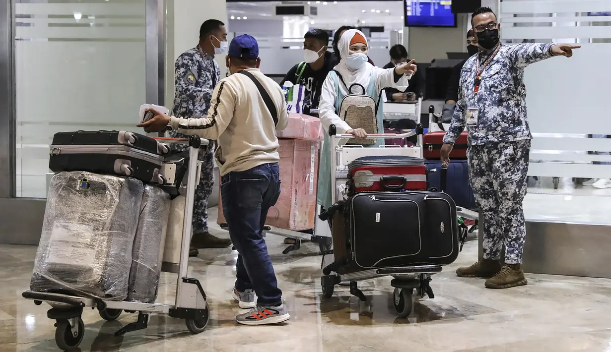 Otoritas Penjaga Pantai Filipina (PCG) membantu penumpang saat mereka tiba di Bandara Internasional Manila, Filipina, Kamis (10/2/2022). Filipina mulai hari ini membuka kembali pintu bagi turis asing setelah hampir dua tahun menutup perbatasannya. (AP Photo/Basilio Sepe)