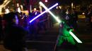 Dua orang pria saling beradu lightsaber (pedang sinar) saat mengikuti Glow Battle Tour di Grand Park, Los Angeles (15/12). Para penggemar ini berkumpul dengan membawa pedang sinar yang beraneka warna. (Photo by Chris Pizzello/Invision/AP)