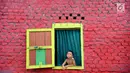 Seorang bocah melongok keluar jendela di Kampung Warna Warni Lubuklinggau, Sumatera Selatan, Rabu (10/1). Kampung yang dulunya menjadi pusat perjudian, sabung ayam, dan lokasi transaksi narkoba itu kini telah berubah wajah (Liputan6.com/Immanuel Antonius)