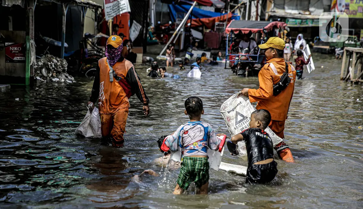 Petugas PPSU membersihkan sampah saat terjadi banjir rob di Pelabuhan Kali Adem, Muara Angke, Jakarta, Selasa (9/11/2021). Walau terendam banjir rob, petugas PPSU tetap sigap bersihkan sampah yang mengambang terbawa air laut. (Liputan6.com/Faizal Fanani)