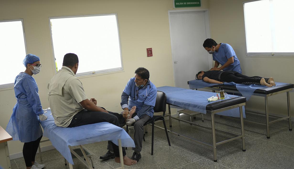 Petugas kesehatan melakukan perawatan pemulihan pasien terpapar virus Corona COVID-19 di pusat kesehatan yang dikelola pemerintah di lingkungan Coche di Caracas, Venezuela pada 25 Februari 2021. (AP Photo / Matias Delacroix)