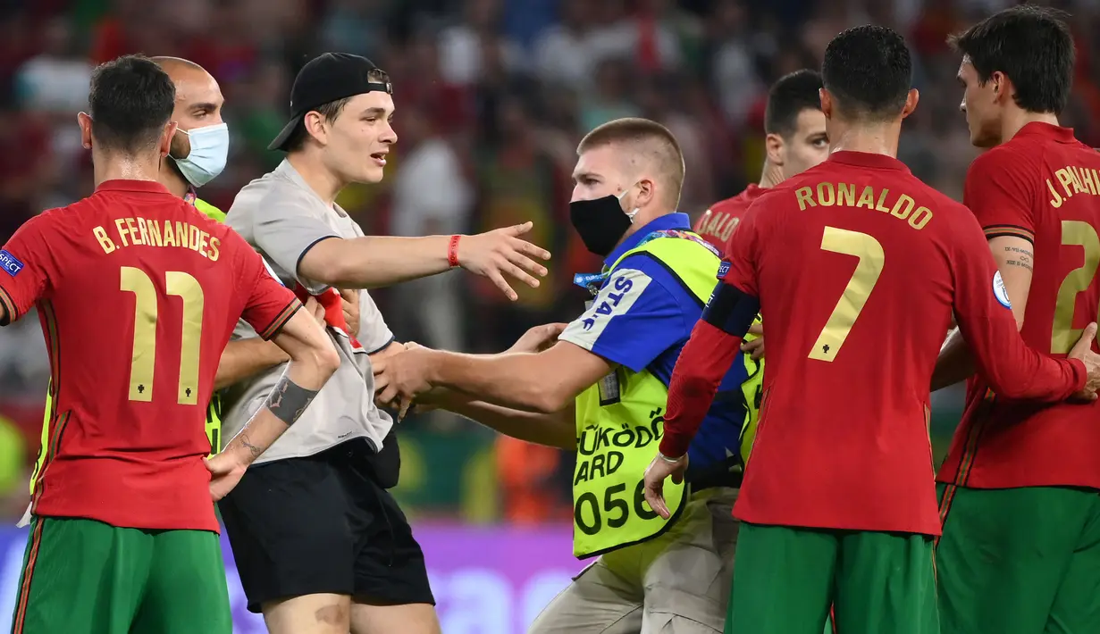Petugas keamanan stadion menahan seorang penyusup lapangan setelah pertandingan sepak bola Grup F UEFA EURO 2020 antara Portugal melawan Prancis yang berlangsung di Puskas Arena, Budapest pada 23 Juni 2021. (AFP/Pool/Franck Fife)