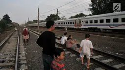 Anak-anak didampingi orang tuanya melihat kereta yang melintas saat menunggu waktu berbuka puasa atau ngabuburit di rel kereta Double Double Track (DDT) di Jakarta, Senin (21/5). (Merdeka.com/Iqbal S Nugroho)