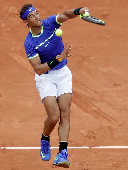 Petenis Spanyol, Rafael Nadal melakukan servis ke arah lawannya petenis Prancis, Benoit Paire pada babak pertama Prancis Terbuka  di Stade Roland Garros, Senin (29/5). Nadal mengalahkan tuan rumah dengan skor 6-1, 6-4, 6-1. (AP Photo/Petr David Josek)