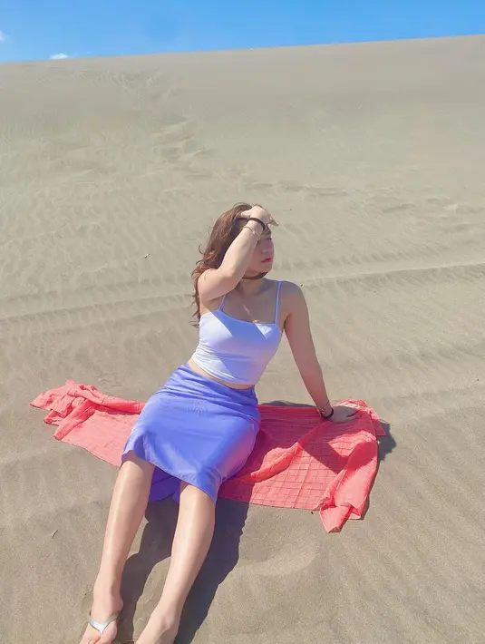 Cassandra Lee seperti saat berpose mengenakan tanktop putih dengan area perut bawah sedikit terlihat. Lalu, dipadukan dengan rok biru selutut. (Instagram/cassandraslee)