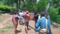 Warga Dusun Glak, Desa Hale, Kecamatan Mapitara, Kabupaten Sikka, NTT sedang menandu pasien melewati jalan rusak menuju puskesmas Mapitara (Liputan6.com/ Dionisius Wilibardus)