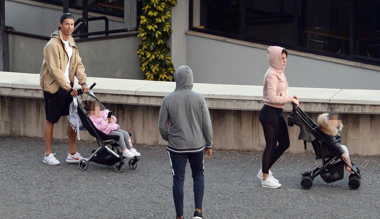 Cristiano Ronaldo bersama kekasihnya Georgina Rodriguez mengajak anak-anaknya berjalan santai di Funchal, Portugal, Sabtu (28/3/2020). Bintang Juventus ini memilih pulang kampung saat Serie A dihentikan sementara karena wabah virus corona. (AFP/Helder Santos)