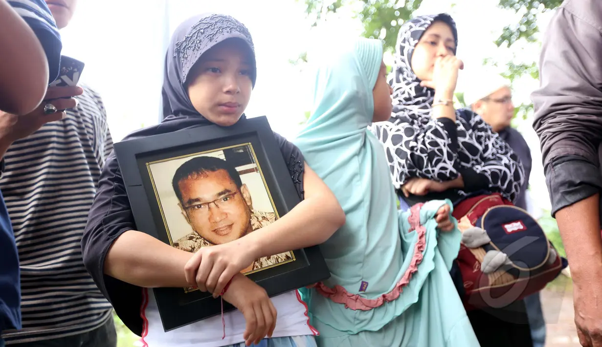 Salah satu anak almarhum Yani Libels membawa foto pria bernama asli Yanni Rusiana Djunaedi itu saat pemakaman di TPU Tanah Kusir, Jakarta, Kamis (26/3/2015).  (Liputan6.com/Panji Diksana)