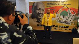 Seorang kader Partai Golkar berpose di depan backdrop Presiden kedua Indonesia, Soeharto disela acara Musyawarah Nasional Luar Biasa (Munaslub) Partai Golkar di Bali Nusa Dua Convention Center (BNDCC), Bali, Minggu (15/5). (Liputan6.com/Johan Tallo)