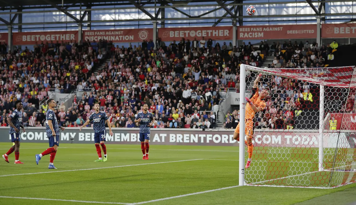 Kiper Arsenal Bernd Leno (kanan) melakukan penyelamatan dari serangan pemain Brentford pada laga pembuka Liga Inggris 2021/2022 di Brentford Community Stadium, Sabtu (14/8/2021) dini hari WIB. The Gunners takluk 0-2 dari tim tuan rumah, Brentford. (Adrian DENNIS/AFP)