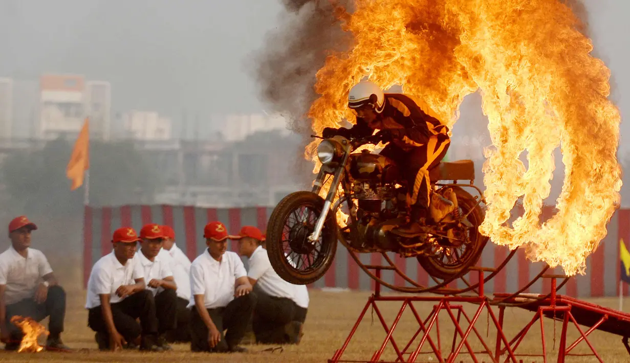 Seorang anggota tentara India dari tim motor 'Tornado' melompati cincin api dengan mengendarai motor selama latihan gabungan di akademi pelatihan perwira di Chennai (9/3). (AFP Photo/Arun Sankar)