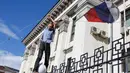 Massa aksi terlihat menurunkan bendera Rusia yang berkibar di halaman Kedutaan Besar di Kiev, Ukraina, (14/6/2014). (REUTERS/Oleg Pereverzev)