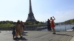 Turis berfoto dengan latar belakang dekat Menara Eiffel di Paris, Rabu (31/8/2022). Pariwisata kembali dengan sepenuh hati ke Prancis musim panas ini, mengirimkan pendapatan melebihi tingkat pra-pandemi menurut data pemerintah yang dirilis minggu ini. (AP Photo/Aurelien Morissard)
