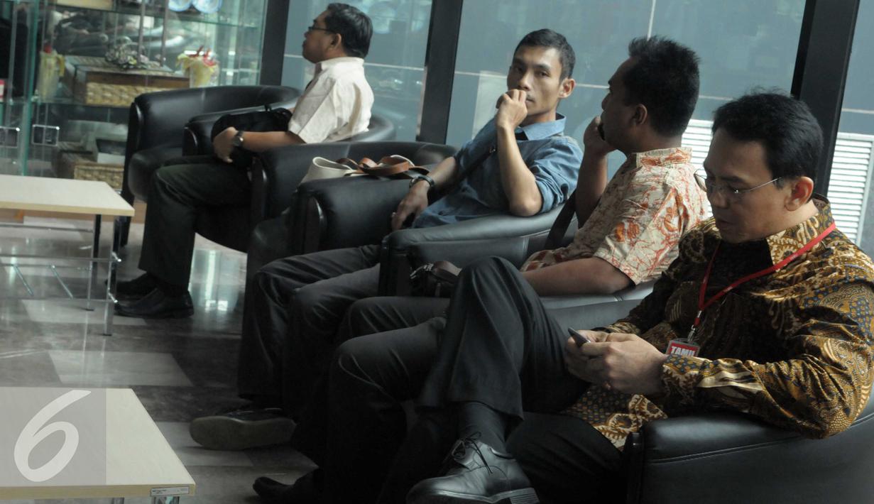 Gubernur DKI Jakarta Basuki 'Ahok' Tjahaja Purnama  bermain ponsel saat menunggu di ruang tunggu KPK, Jakarta, Selasa (12/4). Ahok memenuhi panggilan KPK terkait pemberian keterangan soal perkara pembelian lahan RS Sumber Waras (Liputan6.com/Helmi Afandi)