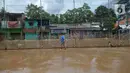 Warga berjalan melewati lumpur sisa banjir di Kelurahan Rawa Jati, Jakarta, Selasa (9/2/2021). Endapan lumpur yang mengendap akibat luapan Kali Ciliwung. (merdeka.com/Imam Buhori)