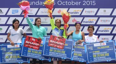 Pelari Nasional, Triyaningsih (tengah) mengangkat tangan usai menerima hadiah lomba lari Jakarta Marathon 2015 di Silang Monas Jakarta, Minggu (25/10/2015). Triyaningsih mencatat waktu tiga jam lima menit 24 detik. (Liputan6.com/Helmi Fithriansyah)