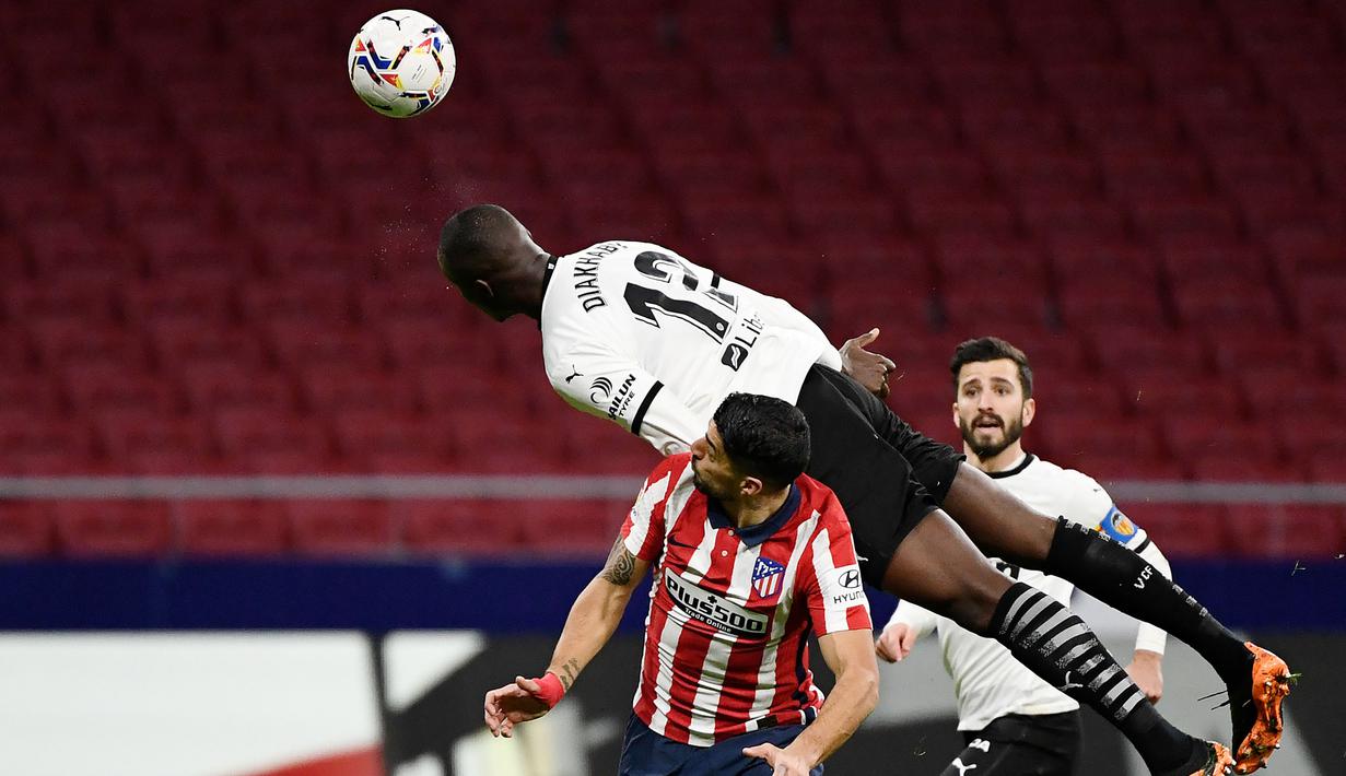 Striker Atletico Madrid, Luis Suarez, duel udara dengan pemain Valencia, Mouctar Diakhaby, pada laga Liga Spanyol di Stadion Wanda Metropolitano, Minggu (24/1/2021). Atletico Madrid menang dengan skor 3-1. (AFP/Pierre Philippe Marcou)