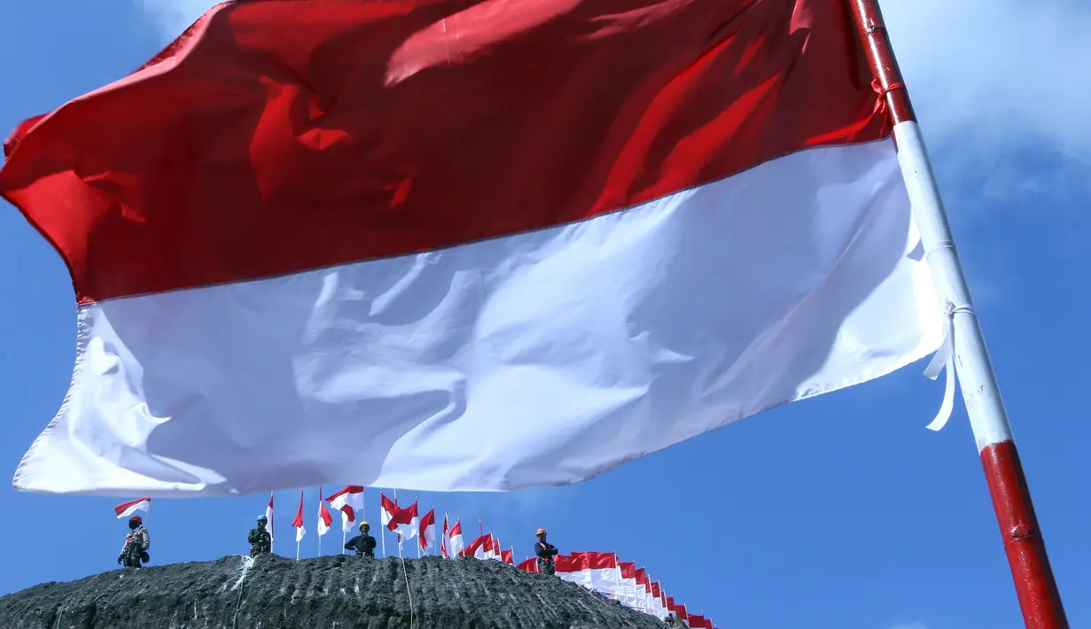 Sejumlah orang berdiri dekat Bendera Merah Putih di dinding tebing Pantai Pandawa, Badung, Bali, Senin (14/8). Barisan pemanjat tebing sebanyak 72 personel dikerahkan dalam kegiatan bertema ‘Pandawa Merah Putih' tersebut. (AP Photo/Firdia Lisnawati)