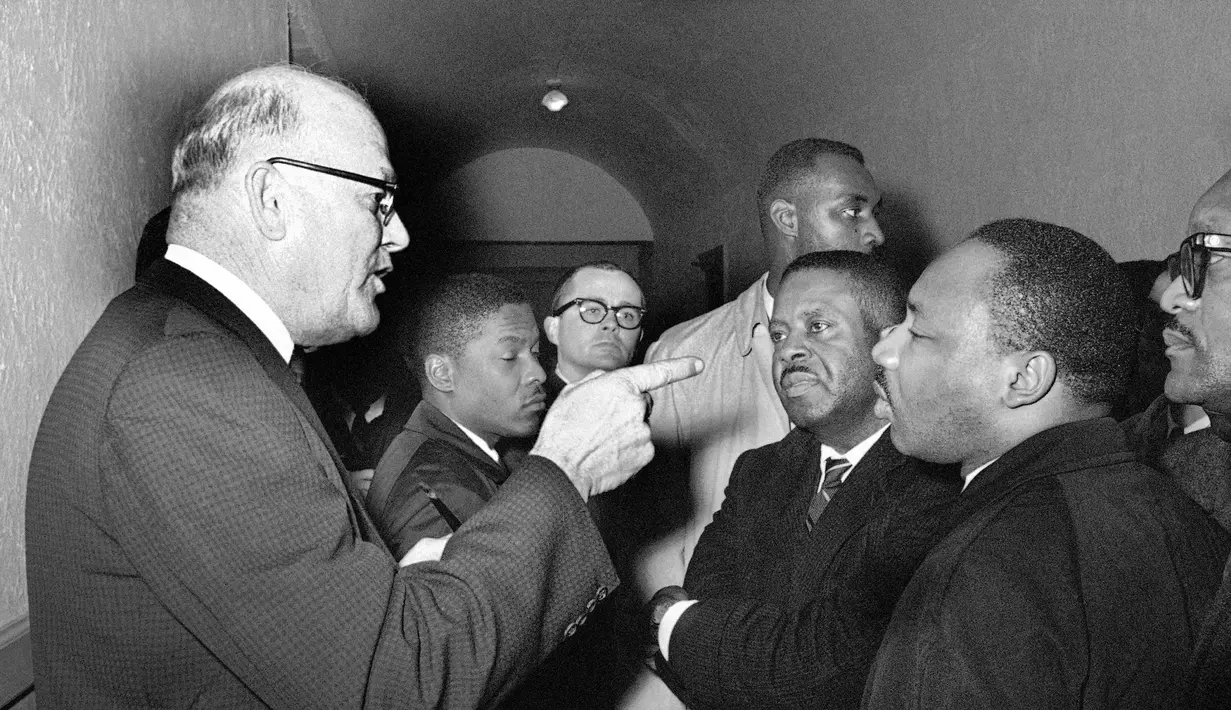 Panitera Carl Golson berbincang dengan Martin Luther King saat menggelar pertemuan di Hayneyville pada 1 Maret 1965. Beberapa bulan sebelum dibunuh, King merasa prihatin dengan masalah ketimpangan ekonomi di Negeri Paman Sam. (AP Photo/Horace Cort, File)