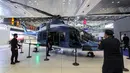 Para peserta berpose untuk difoto dengan helikopter transportasi/utilitas Turkish Aerospace Industries T625 Gökbey yang dipamerkan pada Pameran Pertahanan Maritim Internasional Doha atau Doha International Maritime Defense Exhibition (DIMDEX) di Doha, Qatar, 21 Maret 2022. (KARIM JAAFAR/AFP)