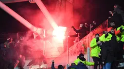 Suporter memegang suar pada pertandingan 64 besar Piala Prancis antara Paris FC dan Olympique Lyon di stadion Charlety, Paris, Jumat (17/12/2021). Pendukung saling bertarung dan beberapa dari mereka turun ke lapangan dan melemparkan suar di babak pertama yang berakhir imbang 1-1. (Bertrand GUAY/AFP)