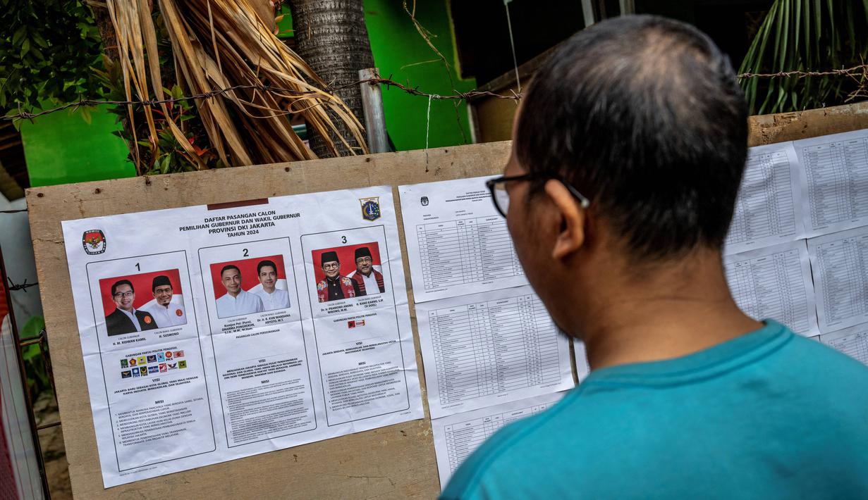 Pemilihan Kepala Daerah (Pilkada) Serentak 2024 berlangsung di 545 daerah meliputi 37 Provinsi, 415 Kabupaten, dan 93 Kota. Tampak dalam foto, seorang pemilih mengamati tiga pasangan calon kepala daerah sebelum memberikan suaranya dalam pilkada serentak di Jakarta pada 27 November 2024. (BAY ISMOYO/AFP)