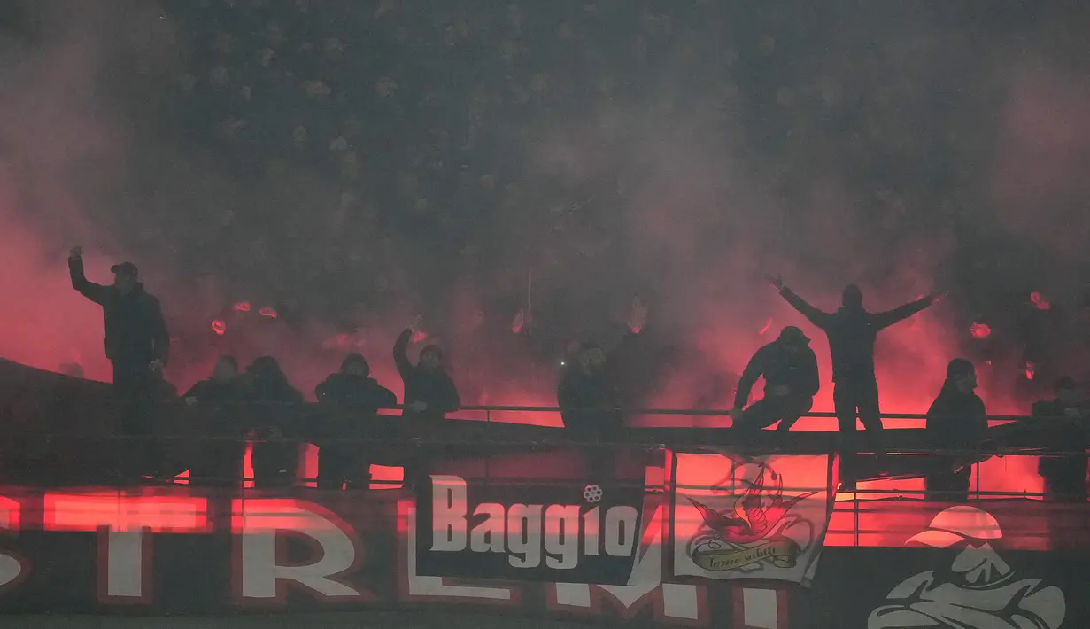 Beberapa pendukung AC Milan bersorak di depan suar yang menyala merayakan gol ke gawang Inter Milan pada laga pekan ke-33 Serie A Liga Italia 2023/2024 di San Siro Stadium, Milan, Senin (22/4/2024). (AP Photo/Luca Bruno)