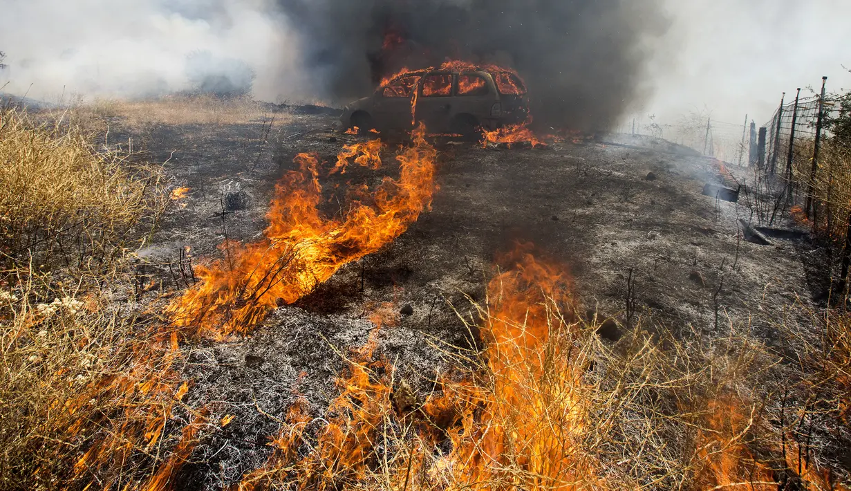 Sebuah mobil yang terbakar akibat kebakaran yang disebut Apple Fire di dekatnya di Cherry Valley, California (1/8/2020). Sebanyak 7.800 warga yang dievakuasi berasal dari 2.586 rumah. Mereka telah diminta untuk mengungsi ke tempat yang lebih aman. (AP Photo/Ringo H.W. Chiu)