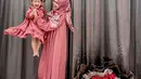 Potret menggemaskan Ria Ricis dengan sang putri Moana. Ricis tampil cantik mengenakan sebuah dress pink yang dipadu dengan hijab bercorak flora yang senada. Moana pun tampil mengenakan dress yang kembar dengan gaya rambut kuncir dua berpita yang manis. [Foto: Instagram/riaricis1795]