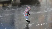 Seorang anak asyik berseluncur melintasi permukaan kanal Prinsengracht yang membeku di Amsterdam, Belanda, Jumat (2/3). Mereka sekarang bisa bermain ice skating di kanal-kanal yang melewati kota. (AP/Mike Corder)