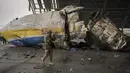 Prajurit Ukraina berjalan di bagian depan pesawat Antonov An-225 Mriya di bandara Antonov di Hostomel, 2 April 2022. Di pintu masuk bandara, pasukan menjaga posisinya, tanda mereka memegang kendali penuh atas landasan pacu yang coba diserbu Rusia di hari-hari pertama perang. (AP Photo/Vadim Ghirda)