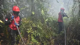 Petugas pemadam kebakaran menyemprotkan air untuk memadamkan kebakaran di Kampar, provinsi Riau pada 17 September 2019. Kebakaran hutan dan lahan (karhutla) yang masih terjadi membuat sejumlah wilayah di Provinsi Riau terpapar kabut asap. (ADEK BERRY / AFP)