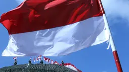 Sejumlah orang berdiri dekat Bendera Merah Putih di dinding tebing Pantai Pandawa, Badung, Bali, Senin (14/8). Barisan pemanjat tebing sebanyak 72 personel dikerahkan dalam kegiatan bertema ‘Pandawa Merah Putih' tersebut. (AP Photo/Firdia Lisnawati)