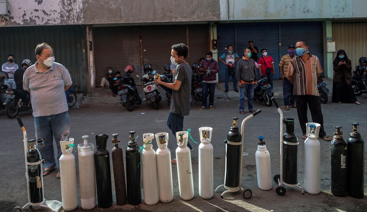 Antrean warga untuk mengisi ulang tabung oksigen di stasiun pengisian di kota Surabaya, Kamis (15/7/2021). Antrean yang terjadi di agen pengisian ulang oksigen itu disebabkan meningkatnya permintaan kebutuhan oleh warga. (Juni Kriswanto / AFP)