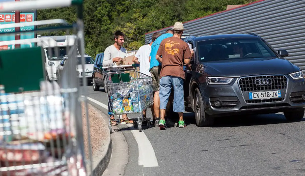 Petani membagikan produk yang diambil dari supermarket Casino kepada pengendara yang lewat di Sarlat, Perancis barat daya, sebagai bentuk demo di supermarket tersebut, Kamis (20/8/2015). (AFP PHOTO/Yohan Bonnet)