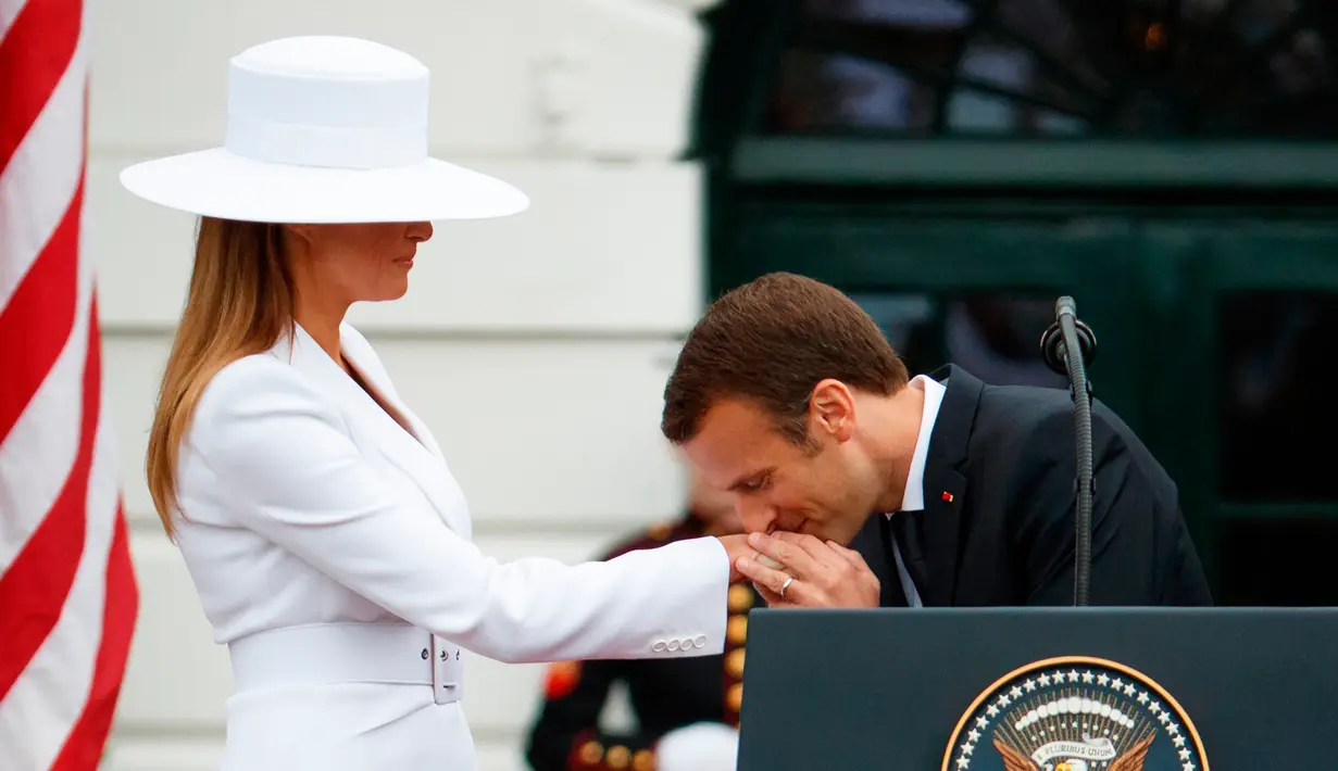 Presiden Prancis Emmanuel Macron mencium tangan Istri Presiden AS Donald Trump, Melania Trump saat upacara menyambut kedatangan tamu negara di Gedung Putih, Washington (24/4). (AP Photo/Evan Vucci)