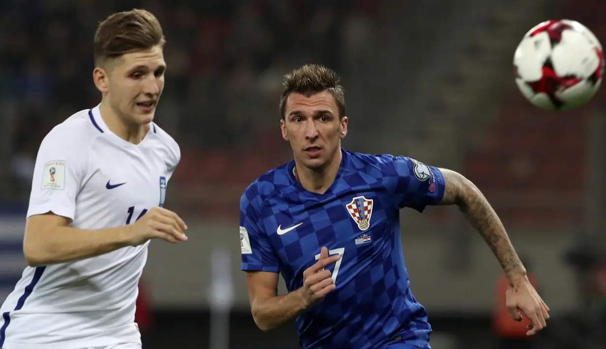 Pemain Kroasia, Mario Mandzukic berebut bola dengan pemain Yunani, Panagiotis Retsos pada laga leg kedua play-off Piala Dunia 2018 di Stadion Karaiskakis, Senin (13/11). Timnas Kroasia berhasil memastikan langkah ke Piala Dunia 2018. (AP/Yorgos Karahalis)