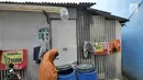 Warga memeriksa tong air di kawasan Kampung Kamal Muara, Jakarta, Selasa (9/7/2019). Sebagian besar warga Kampung Kamal Muara memasang pipa pada talang air di tepi atap rumah mereka untuk menampung air hujan. (Liputan6.com/Herman Zakharia)
