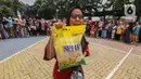 Warga membawa beras Stabilisasi Pasokan dan Harga Pangan (SPHP) usai membeli digelaran Gerakan Pangan Murah di Pinang, Kota Tangerang, Banten, Selasa (20/2/2024). (Liputan6.com/Angga Yuniar)
