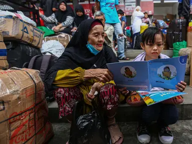 Anak-anak yang hendak ikut dalam perjalanan mudik membaca buku yang diberikan secara cuma-cuma oleh Badan Bahasa Kementerian Pendidikan, Kebudayaan, Riset, dan Teknologi (Kemendikbudristek) di Teriminal Kalideres, Jakarta, Selasa (2/4/2024). (Liputan6.com/Angga Yuniar)