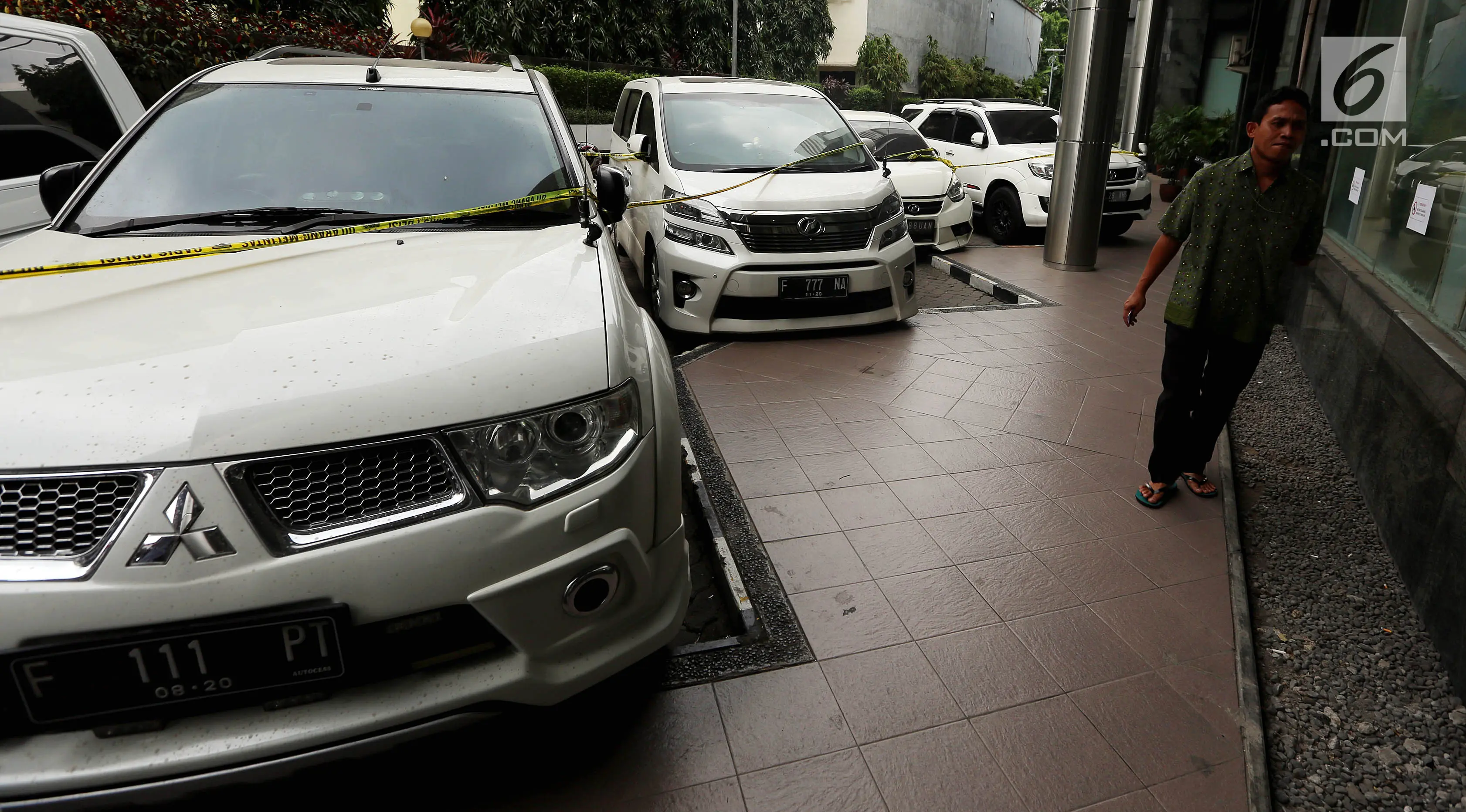 Seorang pria melewati deretan mobil mewah bos PT First Travel Andika Surachman dan Anniesa Hasibuan di Bareskrim Polri, Gedung KKP, Jakarta, Jumat (25/8). Mobil itu disita terkait kasus penggelapan dan penipuan jemaah umrah (Liputan6.com/Johan Tallo)