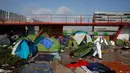 Seorang pekerja balai kota Paris membersihkan sebuah tenda pengungsian migran di Paris, Prancis (30/5). (AP/Thibault Camus)