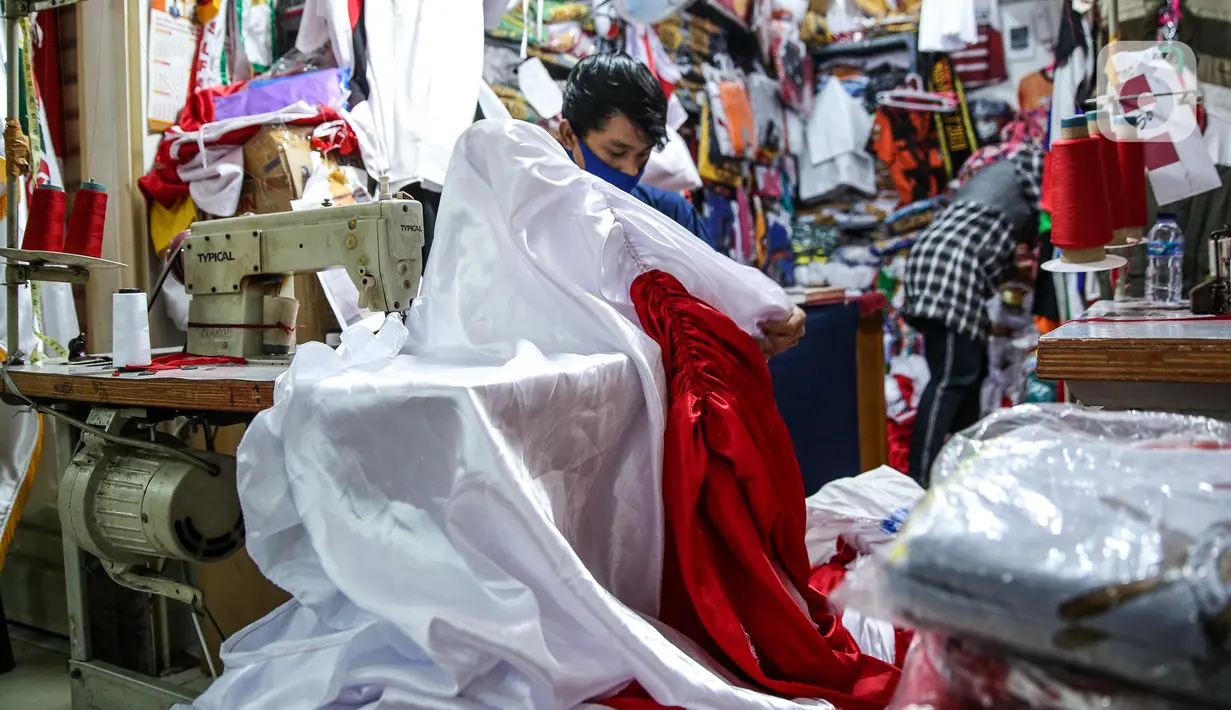 Pekerja menjahit bendera merah putih di kiosnya, kawasan Pasar Senen, Jakarta, Rabu (5/8/2020). Menjelang peringatan HUT ke-75 Kemerdekaan RI, sejumlah pedagang mengaku penjualan pernak-pernik bendera merah putih menurun 50 persen dibanding tahun lalu akibat COVID-19. (Liputan6.com/Faizal Fanani)