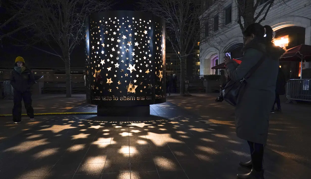Orang-orang berfoto di "The Stars Come Out At Night" oleh Stellar Projects, sebagai bagian dari festival Winter Lights di Canary Wharf, di London, Rabu (18/1/2023). Festival ini menerangi Canary Wharf dengan koleksi spektakuler lebih dari 20 instalasi. (AP Photo/Alberto Pezzali)