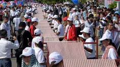 Warga Kamboja membentangkan syal krama sepanjang 1.149,8 meter untuk memecahkan rekor Guinness sebagai syal tenun terpanjang dunia di Phnom Penh, Minggu (1/7). Lebih dari 23.000 orang berpartisipasi membentangkan syal tersebut. (AFP/TANG CHHIN Sothy)